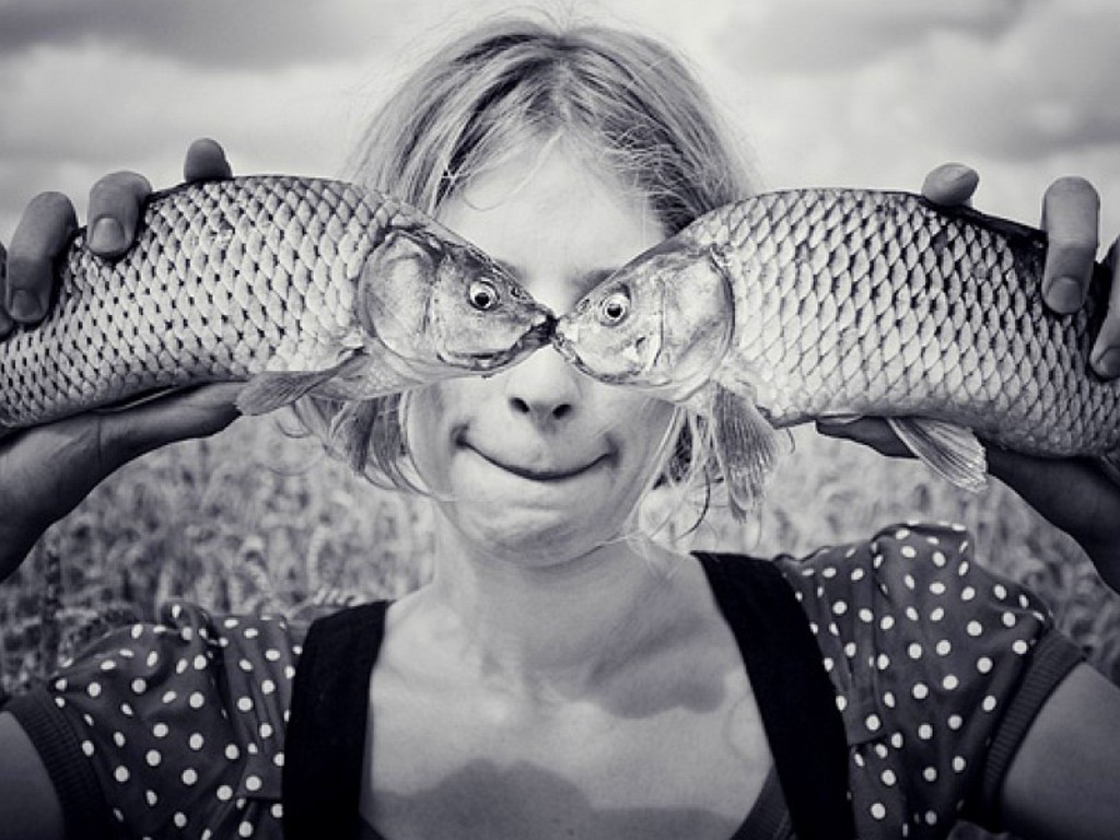 Creative optical illusion — fish held in front of a face so the fish eyes align with human eyes, a memorable double-take